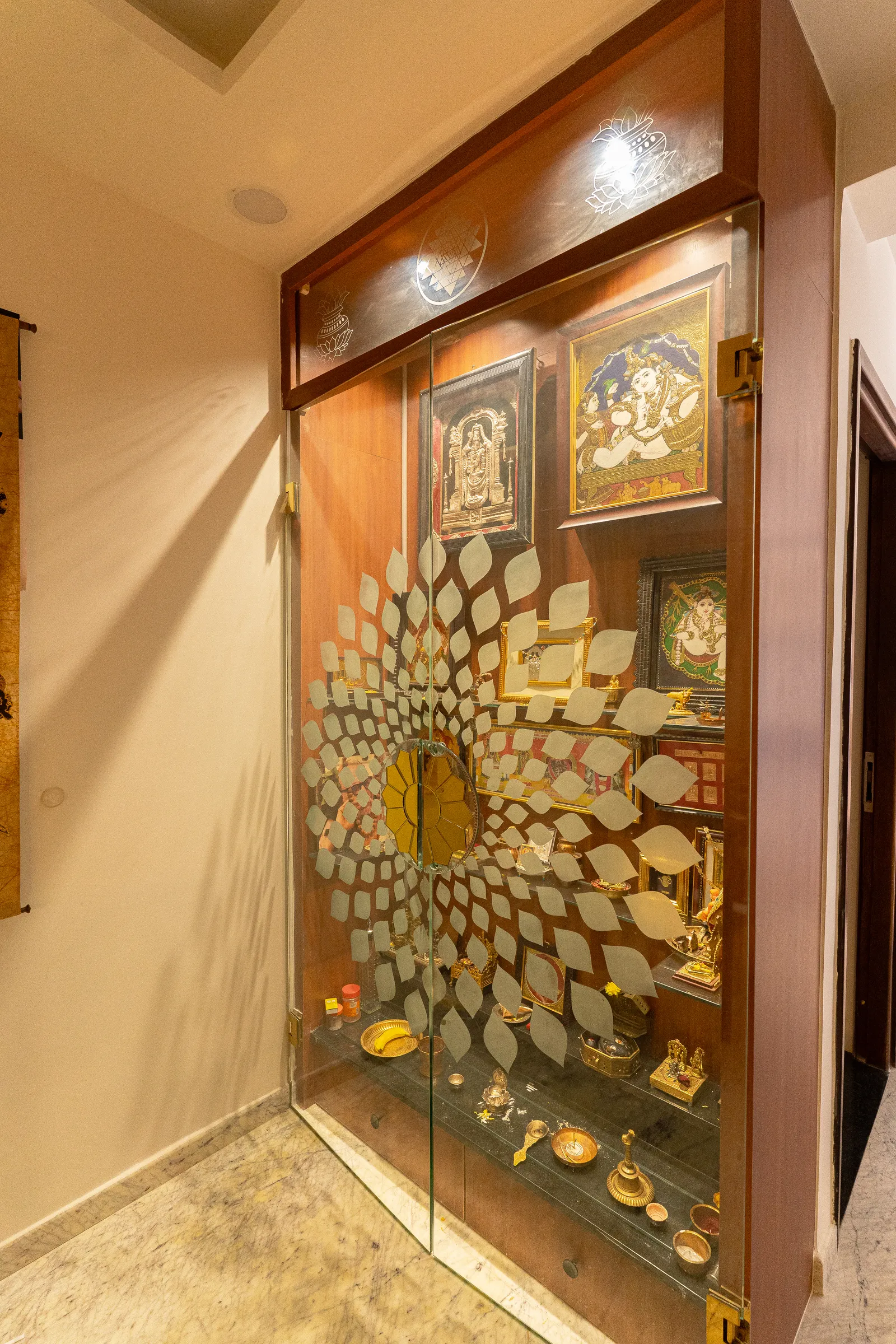 Pooja room with glass door etched in a gold peacock motif — Karthik's Residence